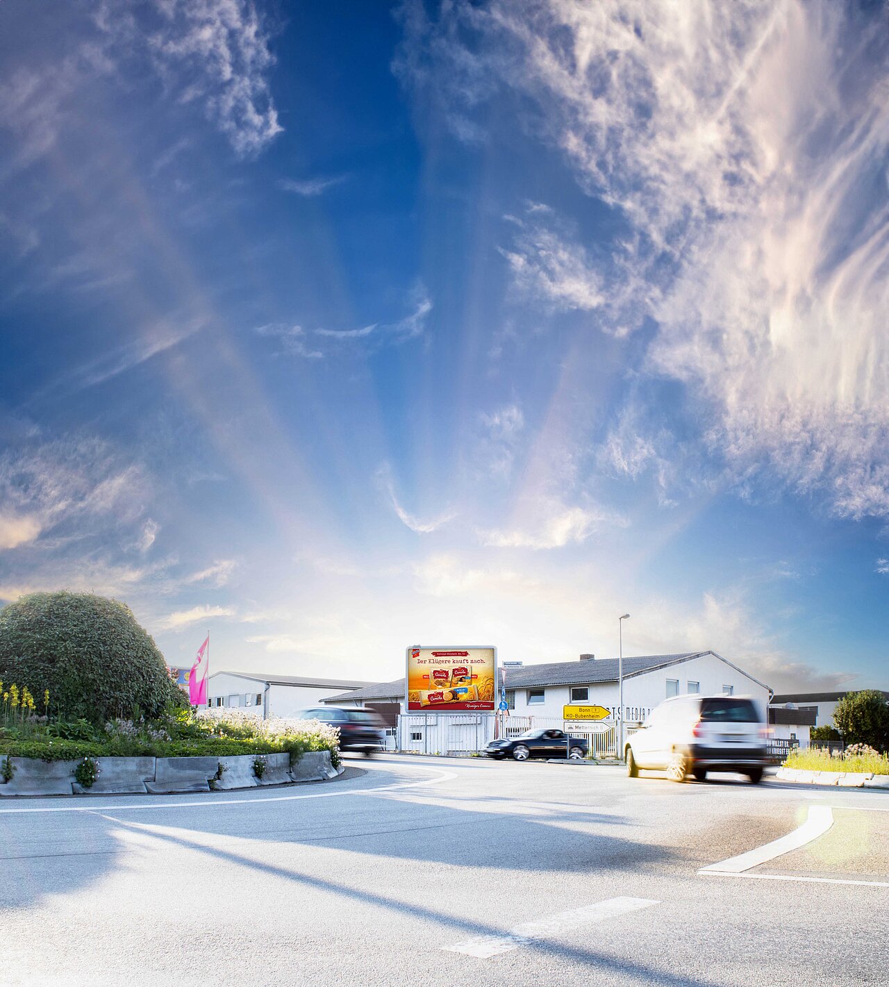 Werbeplakat mit dem Slogan 'Der Klassiker – jetzt probieren!' in einem belebten Verkehrskreisel. Das Plakat ist gut sichtbar für Autofahrer und Passanten.