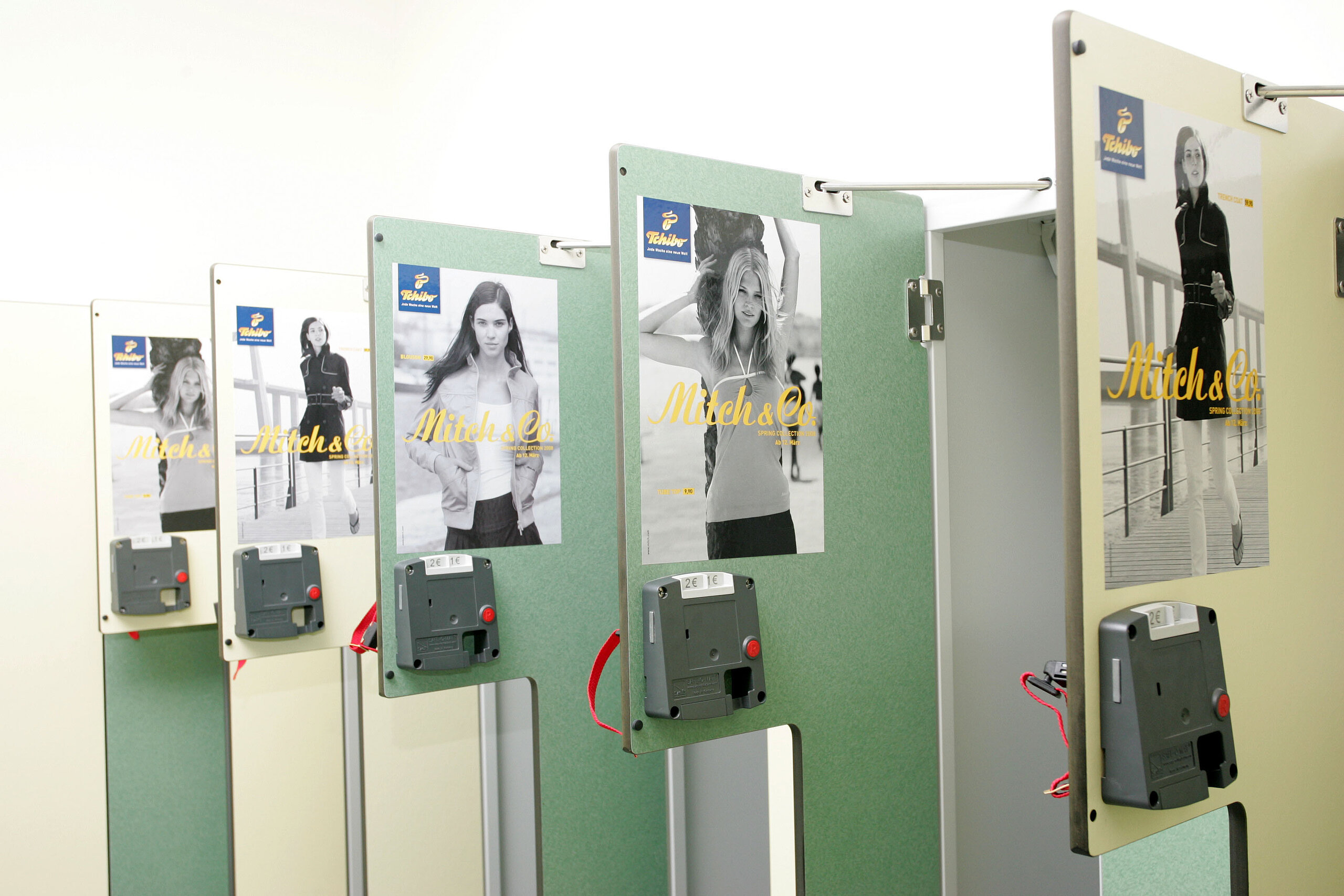 Mehrere Spindtüren in einer Umkleide mit angebrachtem Werbeplakat von Tchibo; typisches Beispiel für Spindplakate in Fitnessstudio, Schwimmbad oder Sauna.