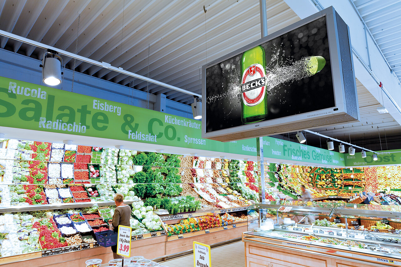 Digitale Werbung mit Beck’s-Motiv auf einem Screen im Supermarkt, ideal für aufmerksamkeitsstarke Außenwerbung am Point of Sale.