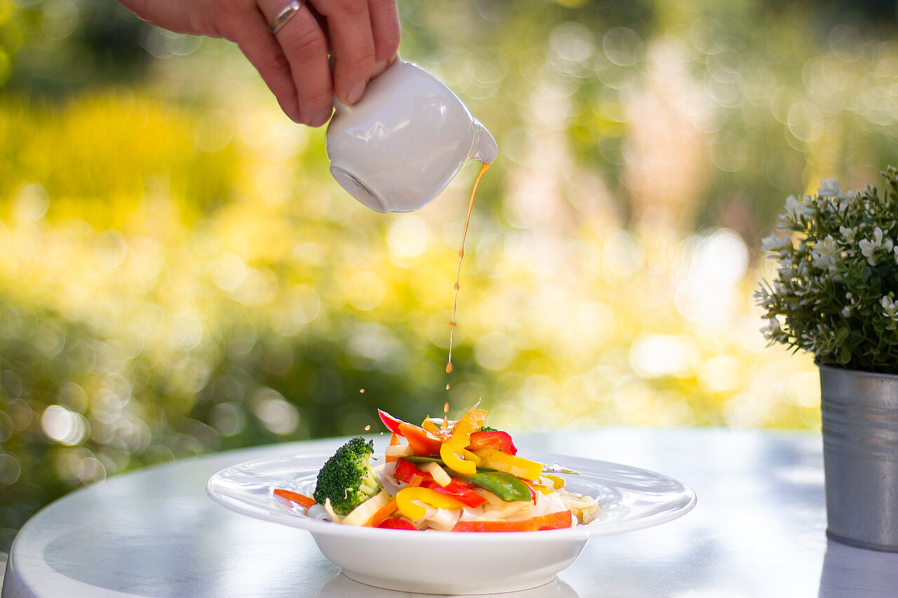 Frisch zubereitetes Gemüsegericht, über das Soße gegossen wird – gesunde und abwechslungsreiche Mittagsverpflegung bei Plakat-verkauft.de.