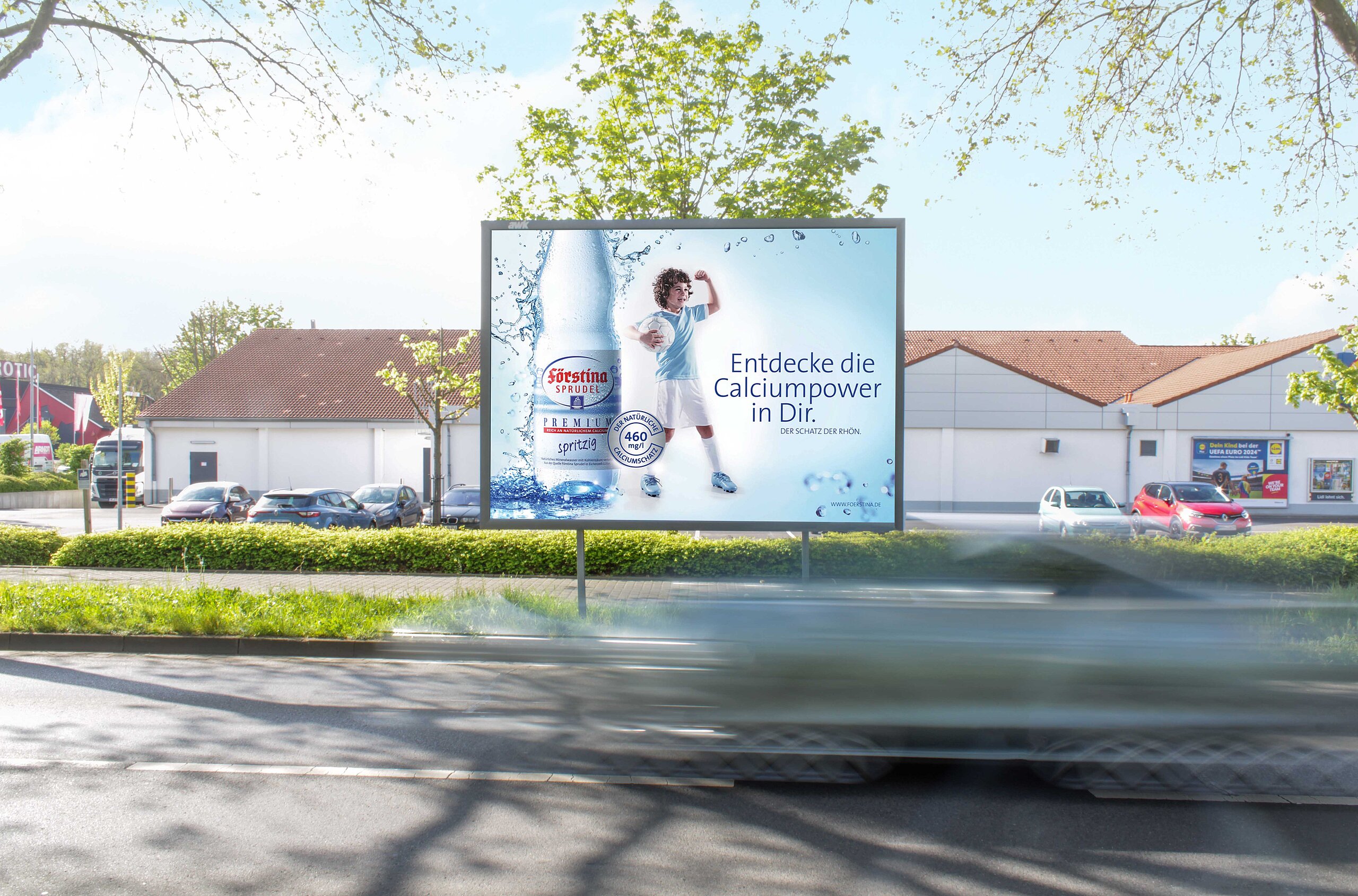 Werbeplakat für Fürstina Sprudel mit dem Slogan 'Entdecke die Calciumpower in Dir' und einem Kind, das eine Flasche Sprudelwasser hält. Das Plakat ist an einer gut sichtbaren Straßenecke platziert.
