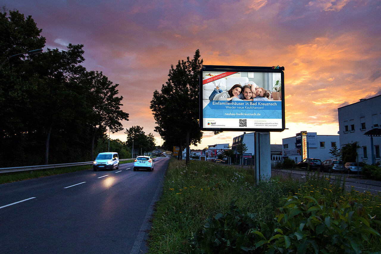 Großfläche am Straßenrand mit Plakatmotiv, das für Immobilienunternehmen wirbt