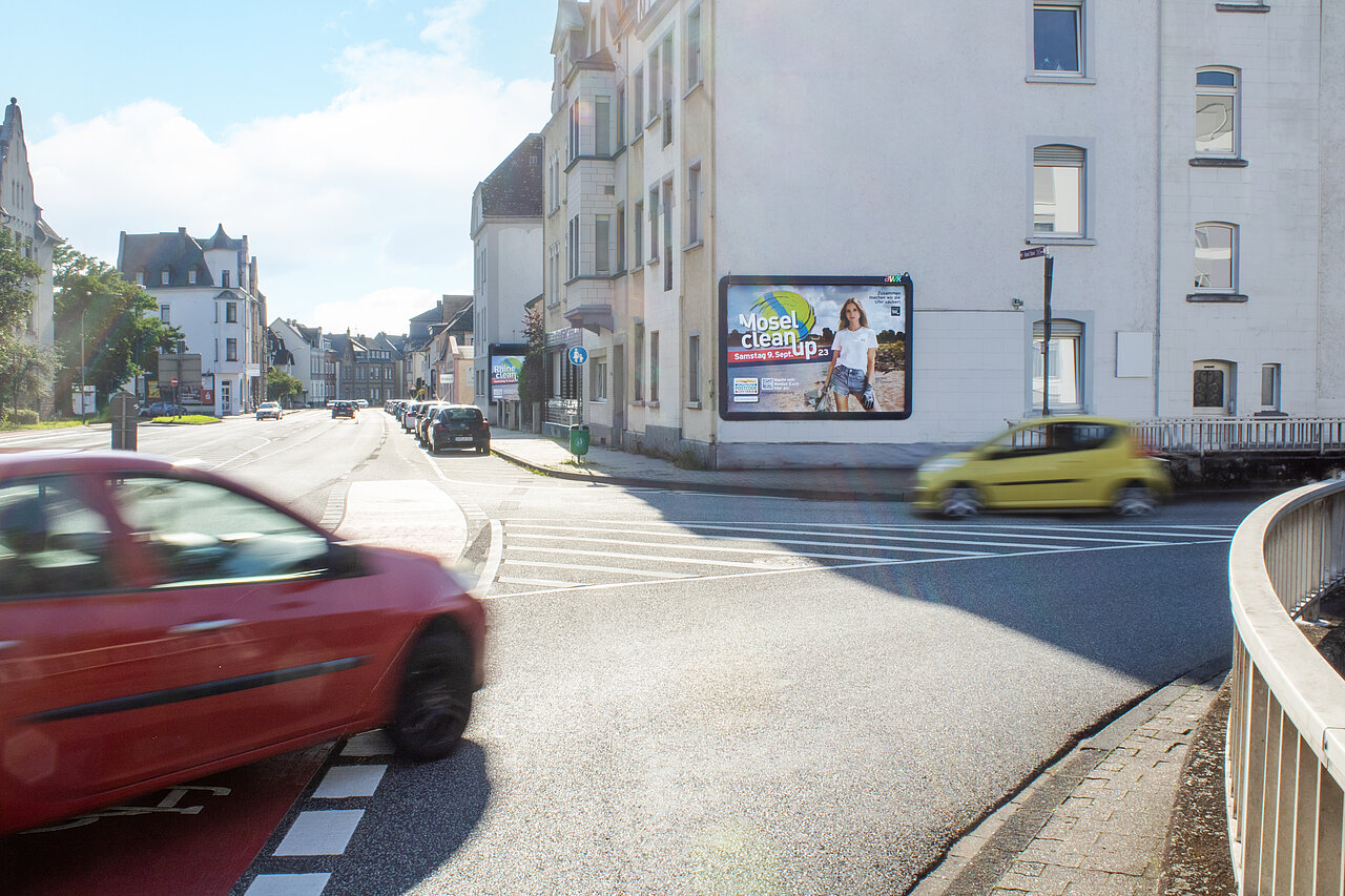 Werbeplakat für das Mosel Clean Up Event. Das Plakat ist an einer belebten Straßenecke platziert.