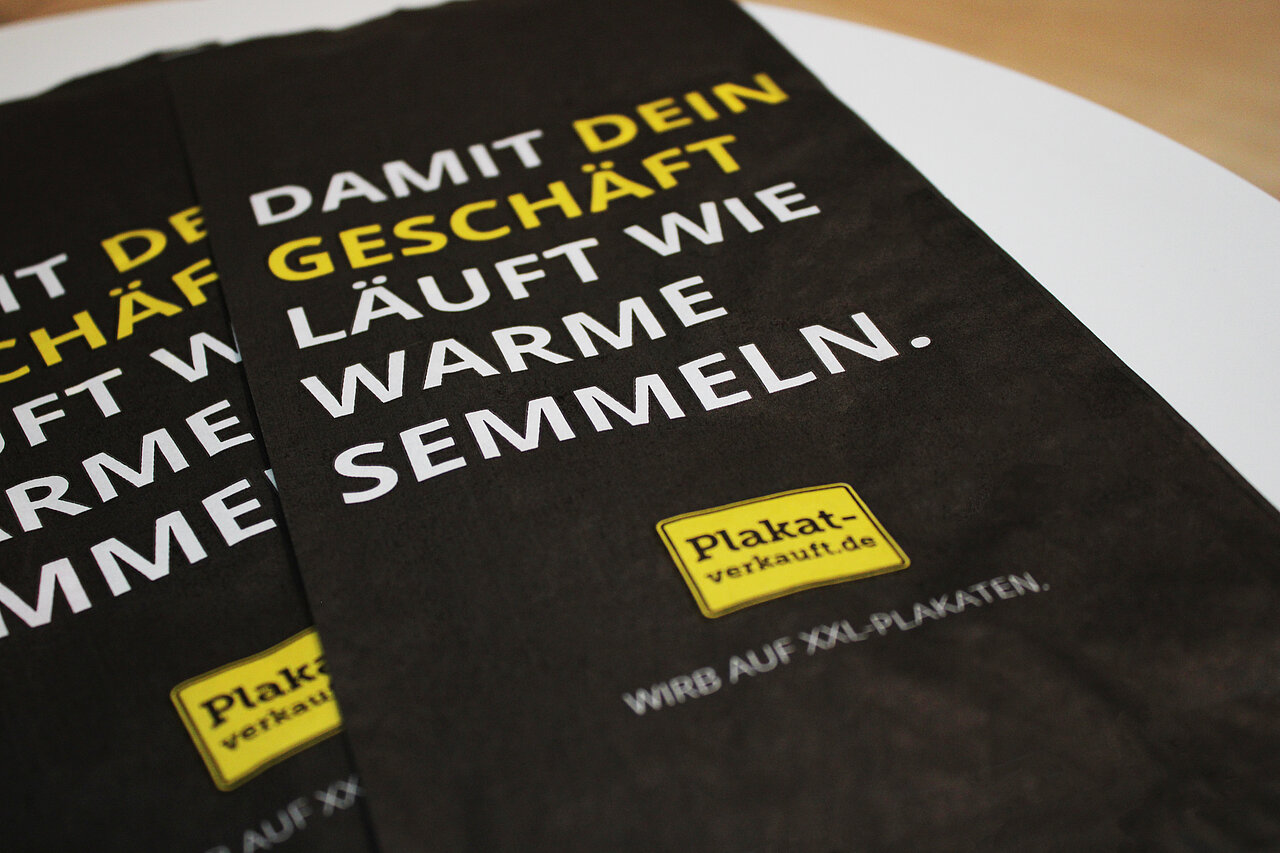 Nahaufnahme bedruckter Ambient Media Brötchentüten mit Werbeslogan „Damit dein Geschäft läuft wie warme Semmeln“