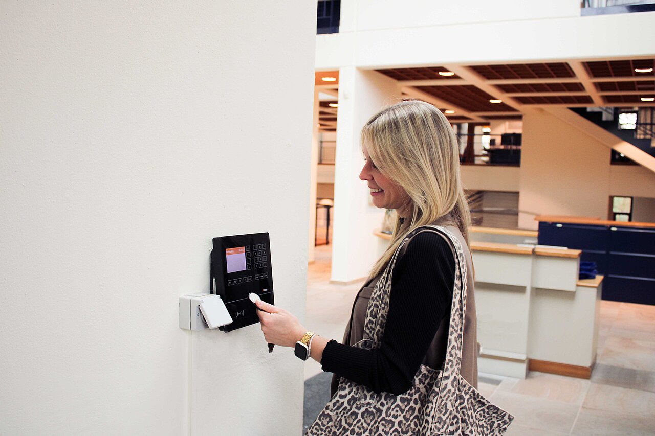 Mitarbeiterin erfasst ihre Arbeitszeit an einem digitalen Terminal – Symbol für flexible Arbeitszeiten und moderne Arbeitsstrukturen bei Plakat-verkauft.de.