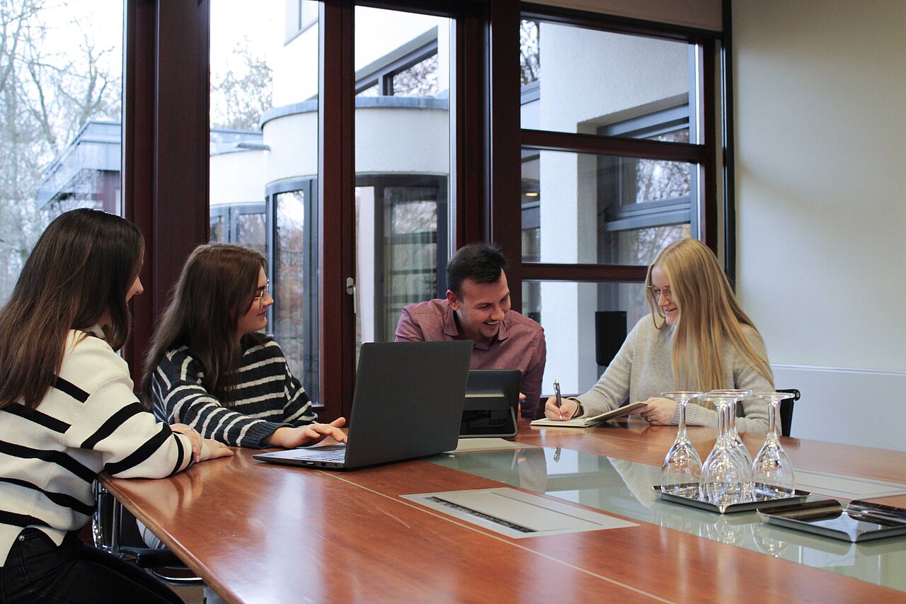 Teammeeting bei Plakat-verkauft.de mit vier Mitarbeitenden, die gemeinsam an Projekten zur Außenwerbung arbeiten und Ideen austauschen.