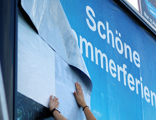 Hände beim Anbringen eines Plakats auf nachhaltigem, ökologischem Papier – umweltfreundliche Außenwerbung von Plakat-verkauft.de.