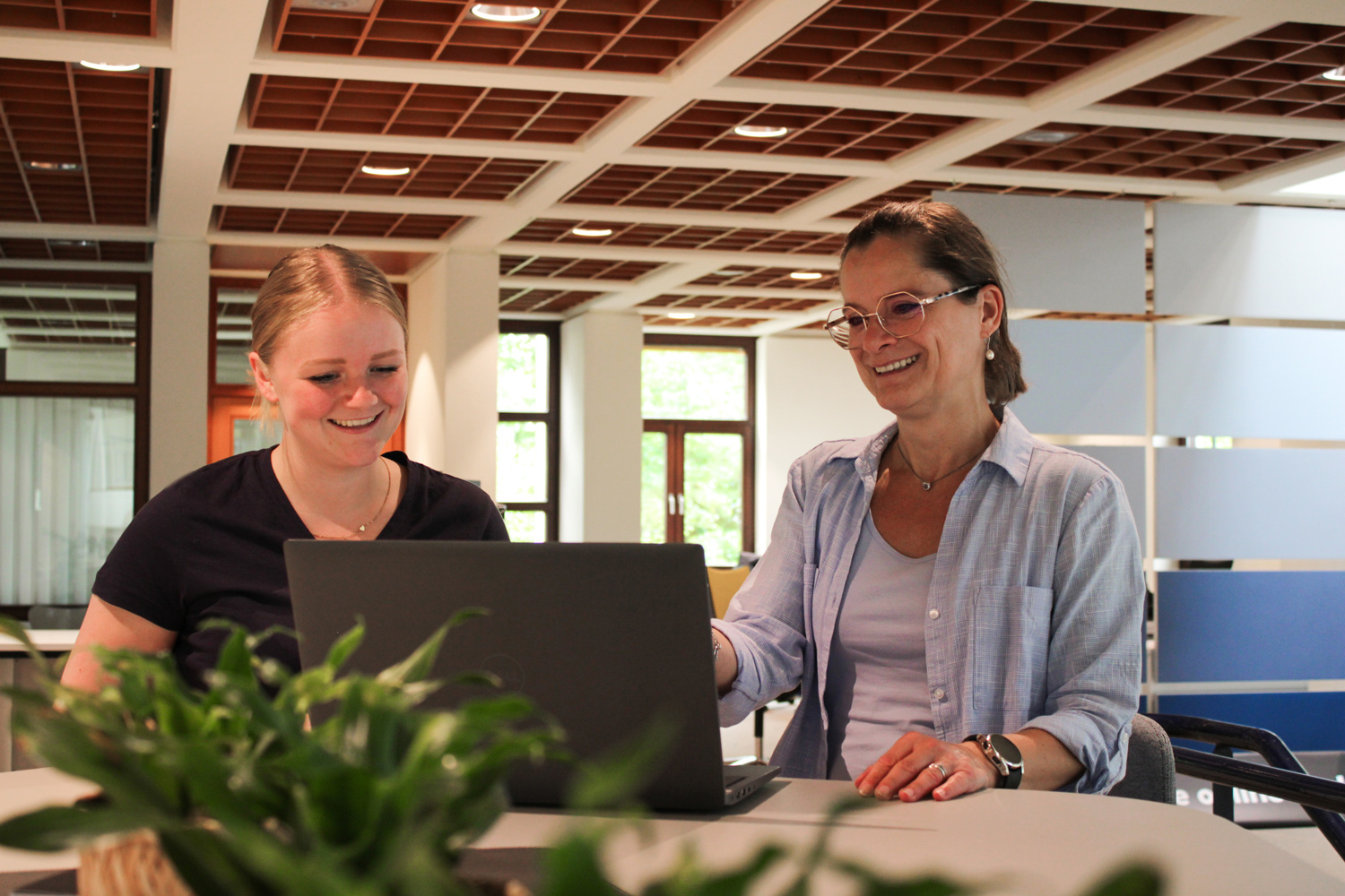 Zwei Mitarbeiterinnen von Plakat-verkauft.de arbeiten gemeinsam an einem Laptop und lachen